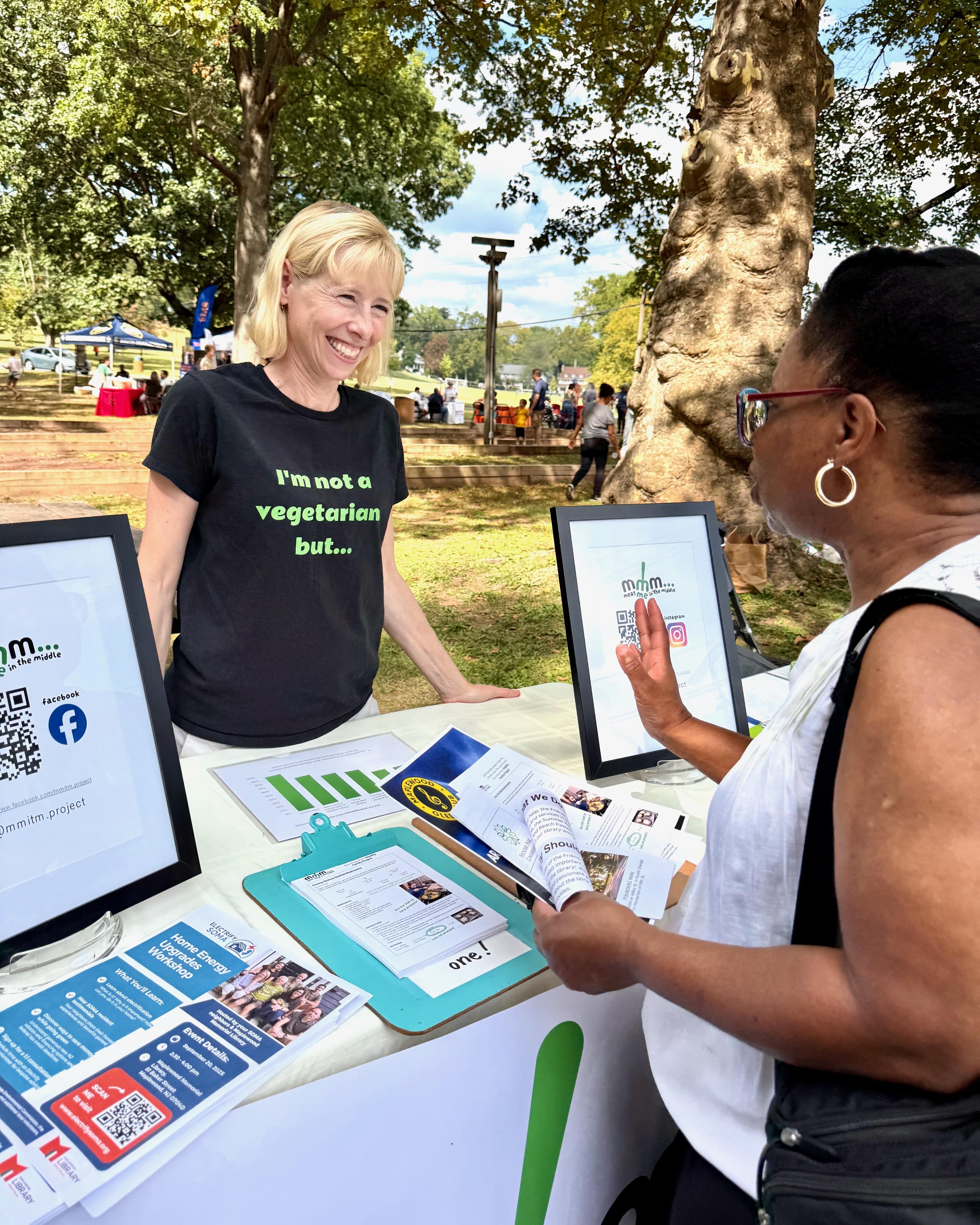 Woman speaks to another woman at a table with informational literature